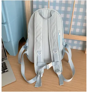 Detailed view of a light blue casual backpack on a wooden desk, showing straps and side pockets.