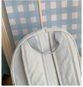 Light blue backpack detail showing shoulder straps and top handle, casual daily school bag style.
