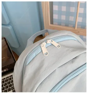 Light blue casual backpack detail showing smooth dual zippers and top handle for daily use.