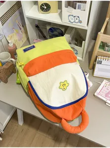 Detailed view of the cute colorblock student backpack with front smiley flower patch and pockets.