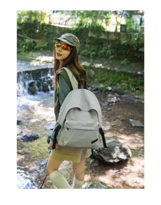 Vue de détail lifestyle en extérieur d'un sac à dos de voyage gris minimaliste en forêt.
