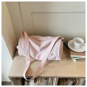 Vue détaillée du sac bandoulière cylindrique en nylon rose, avec sangle réglable et style décontracté.