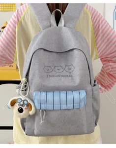 Nahaufnahme eines grauen Rucksacks aus Segeltuch mit süßer Bärenstickerei und blauer Tasche.