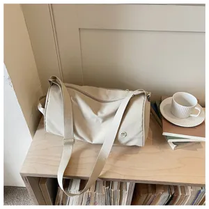 Sac bandoulière cylindrique en nylon beige minimaliste, grand sac porté croisé décontracté.