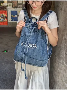 Vintage washed denim backpack for women, casual student school bag with drawstring design.