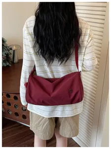 Vue détaillée du sac porté épaule en nylon bordeaux, montrant le tissu souple et la sangle.