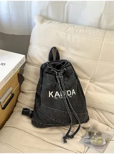 Vintage washed black denim backpack detail showcasing drawstring design and embroidered lettering.