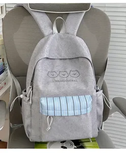Detailansicht des grauen Freizeit-Rucksacks mit blauer Streifentasche und süßer Bärenstickerei.