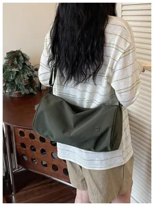 Vue détaillée du sac porté cylindrique en nylon vert foncé élégant sur le mannequin.