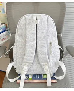Lockerer grauer Rucksack mit weißen Trägern, ideal für Schule und den Alltag geeignet.