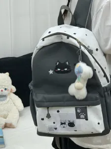 Gedetailleerd overzicht van de schattige zwart-witte rugzak met kattenborduurwerk en pluche hanger.