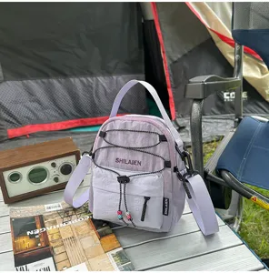 Bolso cruzado ligero de nailon morado con cordón y bolsillo frontal para viajes al aire libre.