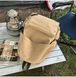 Vue détaillée du sac à dos kaki minimaliste et décontracté en scène de camping en plein air.