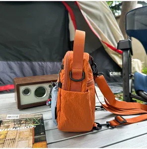 Vista detallada del bolso cruzado de nylon naranja para exteriores con correas y bolsillos.