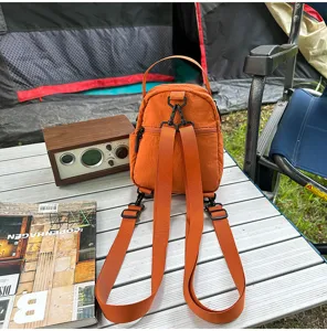 Vista detallada de la mochila mini de nailon naranja, bolso casual de viaje en mesa de camping.