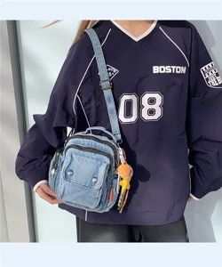 Denim crossbody bag detail showing multi-compartment zipper pockets and casual streetwear style.