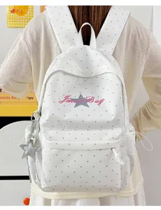 Witte polkadot-rugzak gedragen op de rug, met sterlogo en schattig hangend detail.