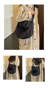 Vue détaillée du sac bandoulière noir à cordon de serrage montrant grande capacité et pliage.