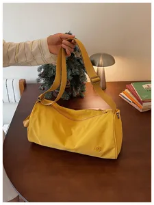 Détail du sac bandoulière cylindrique en nylon jaune avec fermeture zippée et sangle réglable.