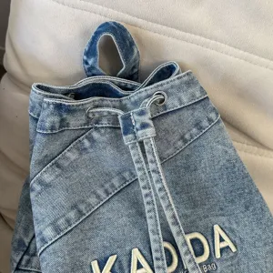 Vintage washed denim drawstring backpack with embroidery details and casual everyday style.