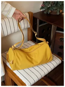 Gros plan sur les détails du sac à bandoulière cylindrique en nylon, montrant la texture.