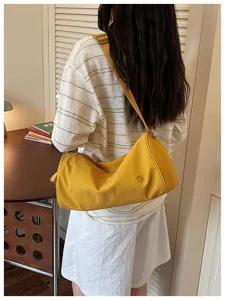 Vue détaillée d'un sac cylindrique en nylon jaune, sac bandoulière décontracté minimaliste.