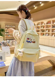 Cute canvas school backpack with adorable dog embroidery detail worn by model in library scene.