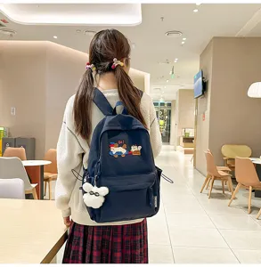 Detail shot of navy blue school backpack with cute animal embroidery and fluffy pendant.