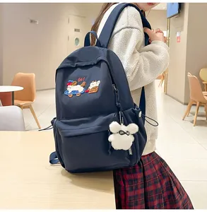 Detailed view of dark blue school backpack with cute embroidered patches and furry pendant.