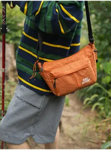 Bolso cruzado de viaje naranja, detalle de tela de nailon resistente y bolsillo.