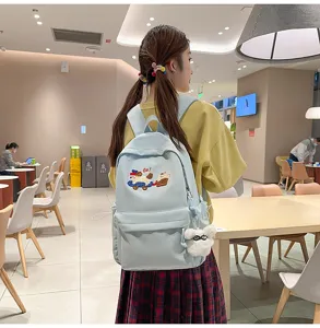 Light blue casual backpack with cute cartoon patch and plush keychain for daily use.