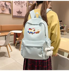 Detail view of the light blue casual backpack with cute dog embroidery and fluffy bear charm.