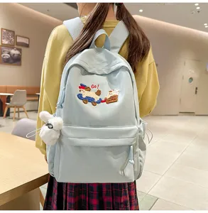 Detailed view of the cute blue canvas schoolbag featuring lovely cartoon embroidery and pendant.