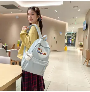 Detailed view of the cute light blue school backpack with sweet embroidery and soft plush charm.
