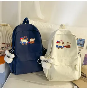 Casual student backpack detail showing cute puppy embroidery and plush rabbit pendant zoom.