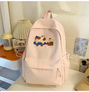 Close-up of the cute pink canvas backpack featuring adorable dog embroidery, soft straps and side pockets.