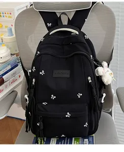 Gedetailleerd overzicht van zwarte rugzak met witte strikprints en schattige pluche konijn hanger.