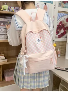 Detailweergave van de roze geruite schoolrugzak met leuke borduursels en strikhanger.