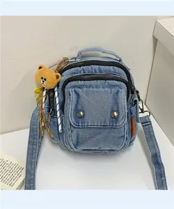 Close-up of casual denim mini backpack showing double zippers and front pocket details.