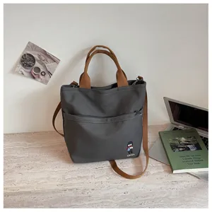 Détail de sac cabas en toile style coréen, avec tissu gris épais et poche avant.