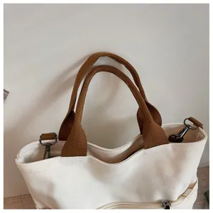 Gros plan sur la poignée et la poche zippée de ce sac cabas en toile, accessoire quotidien idéal.