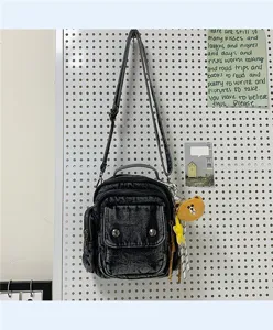 Detailed view of dark denim crossbody shoulder bag with multi pockets and bear plush pendant.