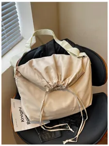 Détail de sac bandoulière beige à cordon, grand sac messager pliant pour un usage quotidien.
