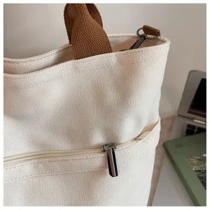 Sac cabas en toile détail gros plan montrant le tissu texturé et une poche zippée.