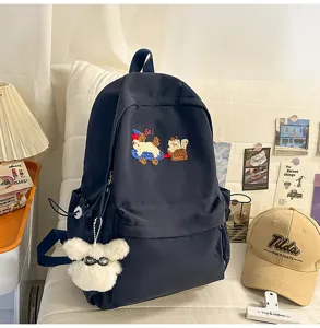 Casual navy blue backpack with cute embroidery and fluffy pendant for school students.