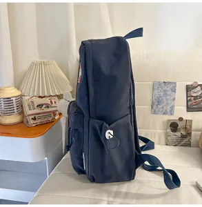 Detail view of a simple dark blue student school bag, lightweight campus backpack with side pockets.