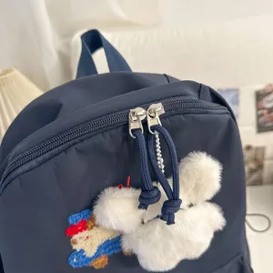 Navy blue school backpack with fluffy plush charm and cute embroidered cartoon design for daily use.