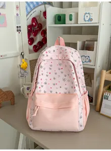 Gedetailleerd overzicht van een schattige roze schoolrugzak met strik- en hartjesprint op een bureau.