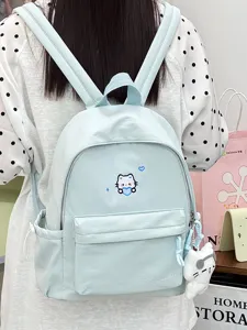 Lichtblauwe canvas rugzak met schattig kattenborduurwerk en bijpassende hanger, gedetailleerd.