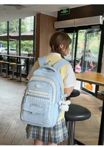 Gedetailleerd overzicht van de esthetische lichtblauwe geruite schoolrugzak in een café.